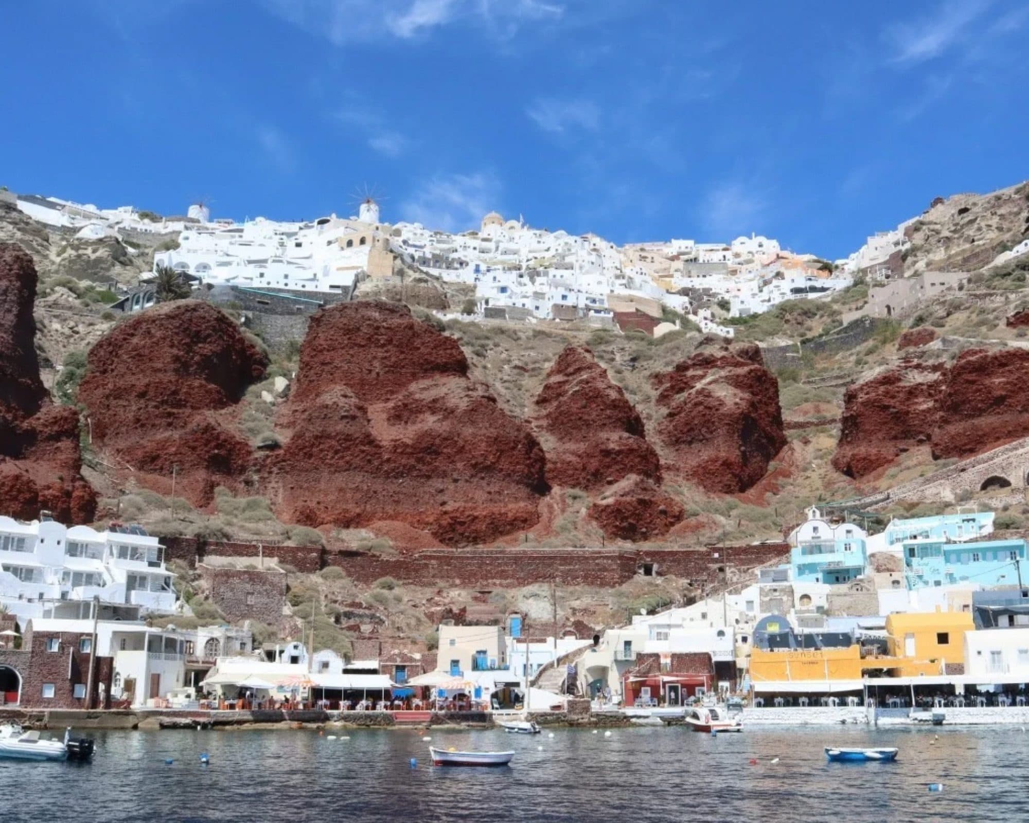 Ammoudi Bay below Oia, with the red cliff and the village on the rim above it