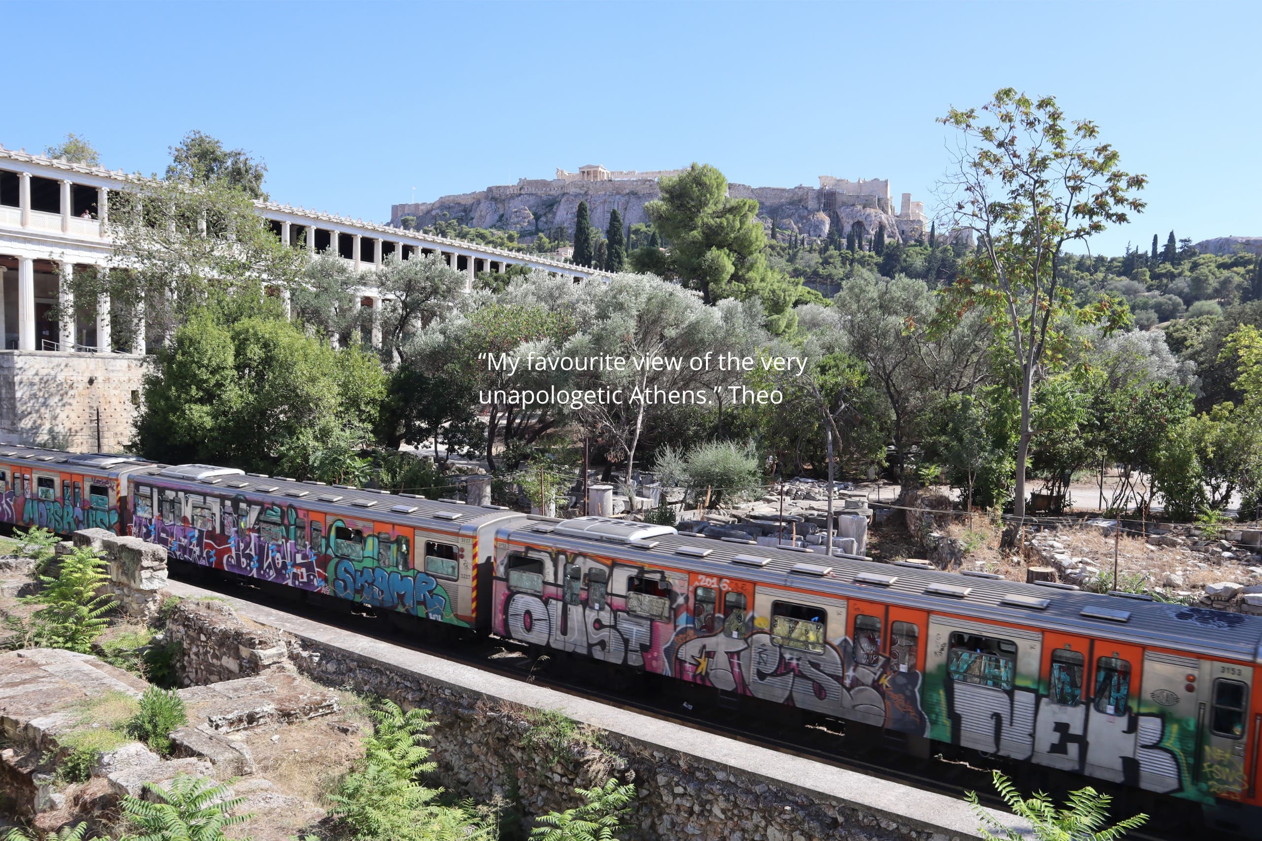 A graffiti-covered Athens metro train passing below the Acropolis — Monobrow Holidays Greece